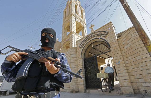 Un soldat irakien monte la garde devant une église à Bartala, à quelques kilomètres de Mossoul. Juillet 2014. Photo : AFP/Karim Sahib